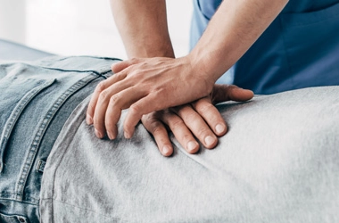 Practitioner performing a manual back adjustment on a patient on a table.