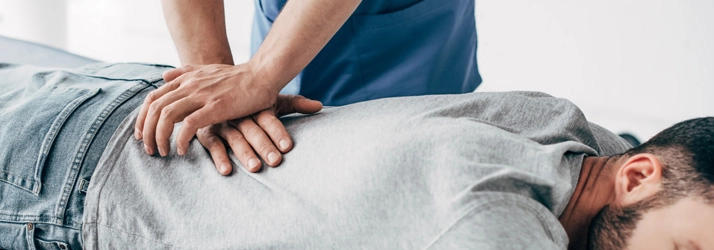 Practitioner performing a manual back adjustment on a male patient on a table.