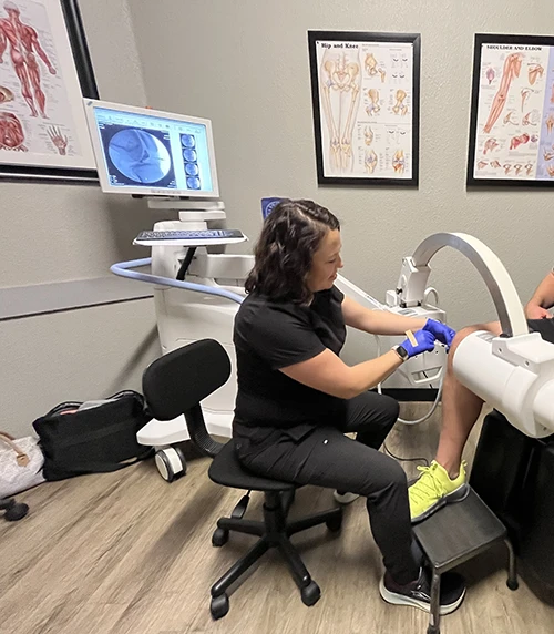 A practitioner performing fluoscopy injection treatment on a patient's knee